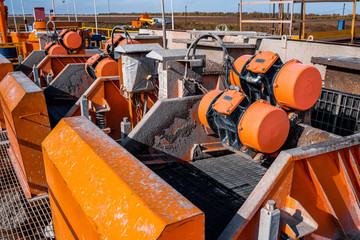 Shale shaker on an offshore oil rig. Shale shaker screen close up view with drill cutting flow out from oil base mud. Separators are end. Equipment for oil separation.