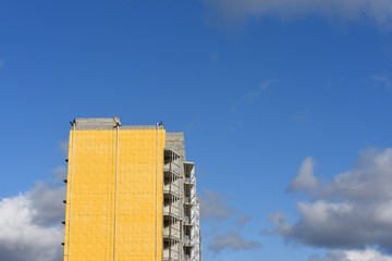 Construction of a high residential building and insulation of its external wall with special heat-insulating material. Wall with thermal insulation against the blue sky