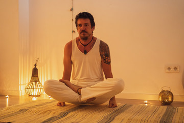 man practicing yoga in a room lit by candlelight