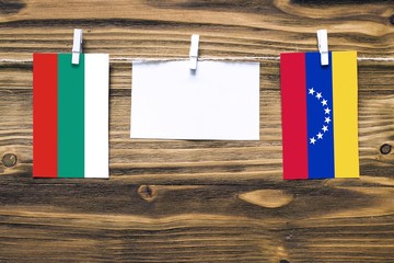 Hanging flags of Bulgaria and Venezuela attached to rope with clothes pins with copy space on white...
