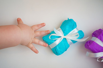 Children's hand reaches for a beautiful gift box on a white background. Holiday Concept. Background. Texture