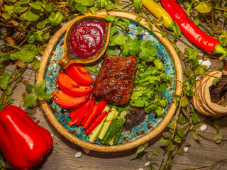 Delicious meat steak with vegetables, tomato and cucumber sliced in strips on craft dishes