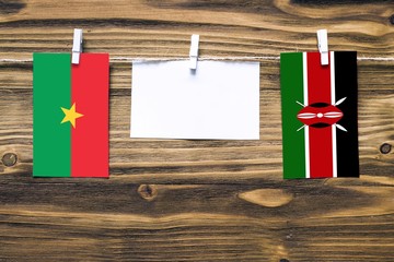 Hanging flags of Burkina Faso and Kenya attached to rope with clothes pins with copy space on white...