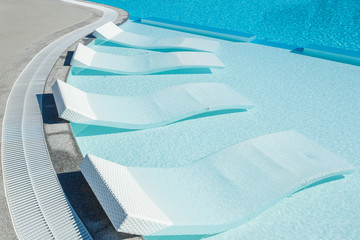 Sun beds. Sun beds in the water. Swimming pool. Relax.