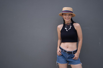 Beautiful Asian women wearing straw hats and black sleeveless tops. Denim shorts Gray backdrop