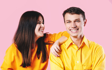 happy young couple in yellow t-shirts laughing on a light background