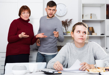 Distressed girl with paperwork and irritated family behind