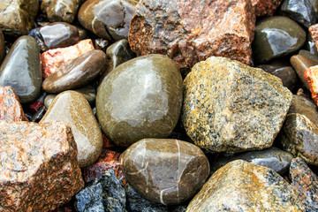 Wet, round stones lie at the bottom of the fountain. Round, big wet pebbles. Stone texture.