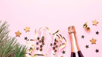 Two champagne glasses with confetti and streamers, golden champagne bottle, green natural fir tree on pastel pink background, copy space. Festive flat lay composition for Christmas or New Year