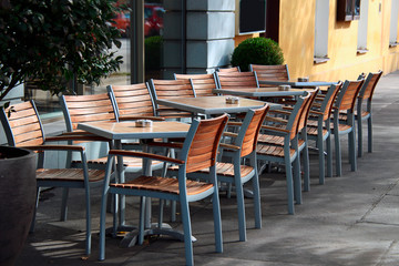 chairs in front of tables with ashtrays in an outdoor cafe