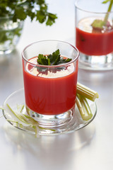 One glass with tomato juice and parsley decoration, a second glass with tomato juice and celery sprig.