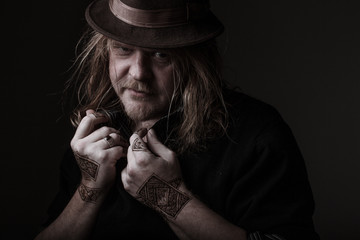 henna man in a brown hat with long hair and drawings