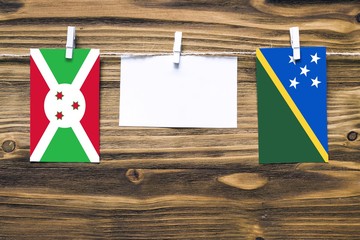 Hanging flags of Burundi and Solomon Islands attached to rope with clothes pins with copy space on...