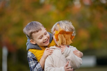 Little boy hugs a girl. Portrait of happy children in bright, autumn clothes. Warm and bright autumn.