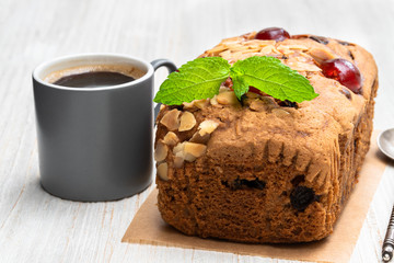 Mixed fruit loaf cake with cup of coffee on wooden table
