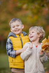 Little boy hugs a girl. Portrait of happy children in bright, autumn clothes. Warm and bright autumn.