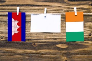 Hanging flags of Cambodia and Cote D'Ivoire attached to rope with clothes pins with copy space on...