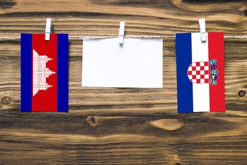 Hanging flags of Cambodia and Croatia attached to rope with clothes pins with copy space on white...