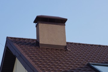 large chimney pipe on a brown tiled roof 