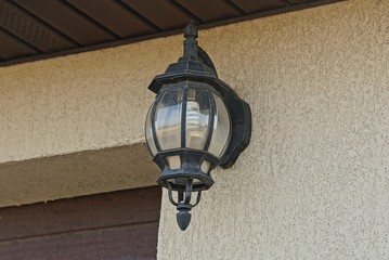 one black metal lamp hanging on a gray wall in the street