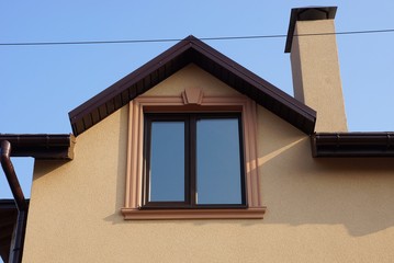 one brown window on the wall of the house with a chimney against a blue sky
