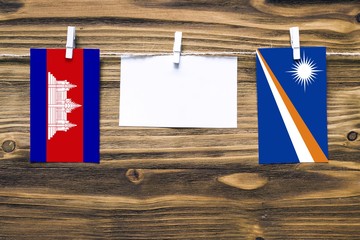 Hanging flags of Cambodia and Marshall Islands attached to rope with clothes pins with copy space...