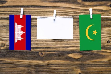 Hanging flags of Cambodia and Mauritania attached to rope with clothes pins with copy space on...