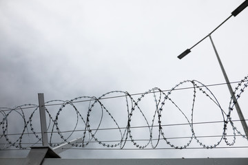 Shallow depth of field (selective focus) and filtered image with a razor wire on the outside wall...