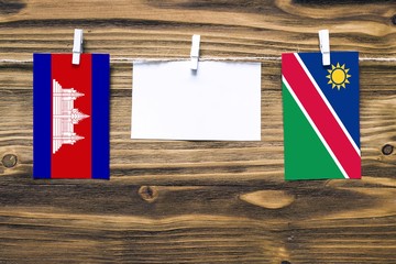 Hanging flags of Cambodia and Namibia attached to rope with clothes pins with copy space on white...