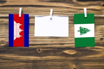 Hanging flags of Cambodia and Norfolk Island attached to rope with clothes pins with copy space on...