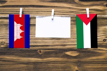 Hanging flags of Cambodia and Palestine attached to rope with clothes pins with copy space on white...