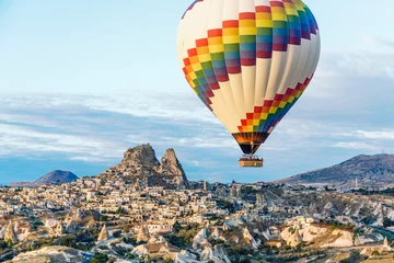 Crédence de cuisine en verre imprimé Ballon Une seule montgolfière lumineuse flotte au-dessus des maisons troglodytes et de la ville de Cappadoce, en Turquie.
