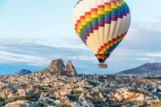 A single bright hot air balloon floats over the cave homes and town in Cappadoccia, Turkey.
