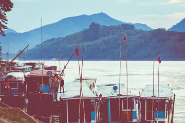 Traditional Long Boat on the Mekong River and mountains view in Luang Prabang, Laos.