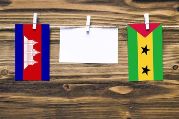 Hanging flags of Cambodia and Sao Tome And Principe attached to rope with clothes pins with copy...