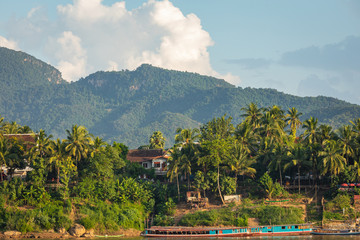Traditional Long Boat on the Mekong River and mountains view in Luang Prabang, Laos.