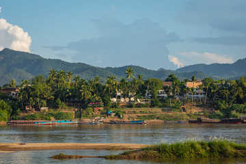 Traditional Long Boat on the Mekong River and mountains view in Luang Prabang, Laos.