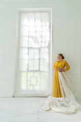 Redhead Woman in Yellow Dress Stands in a White Room
