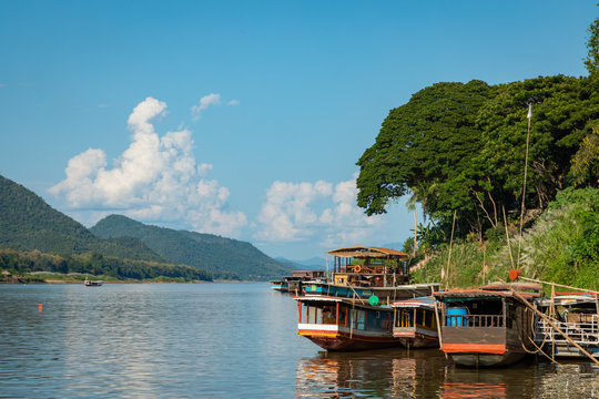Traditional Long Boat on the Mekong River and mountains view in Luang Prabang, Laos.