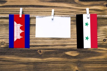 Hanging flags of Cambodia and Syria attached to rope with clothes pins with copy space on white...