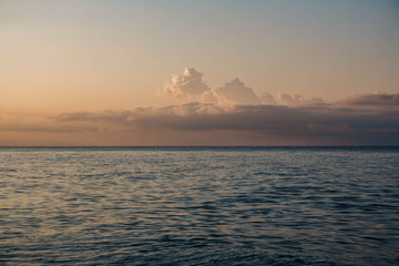 Fototapeta premium Sunset at sea. Beautiful sunset on the beach and sea. Clouds above the horizon line.