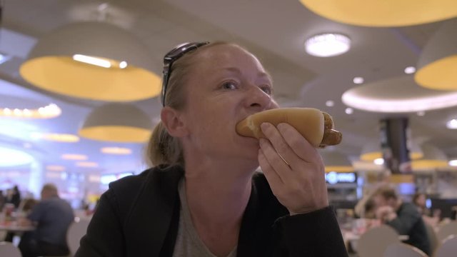 Adult woman greedily eating hot dog.Hungry man eats fast food.