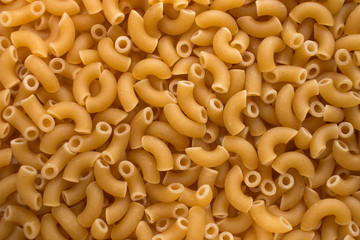 Raw elbow macaroni closeup background texture image.