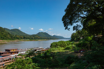 Fototapeta premium Traditional Long Boat on the Mekong River and mountains view in Luang Prabang, Laos.