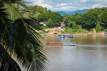 Traditional Long Boat on the Mekong River and mountains view in Luang Prabang, Laos.