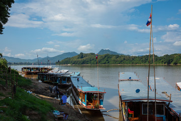Traditional Long Boat on the Mekong River and mountains view in Luang Prabang, Laos.