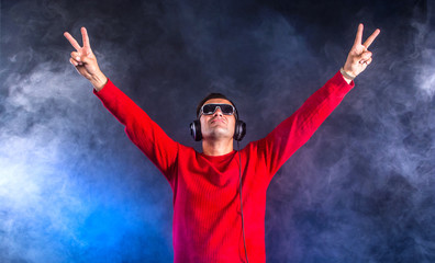 Clubber Dj in headphones with hands up in the night club