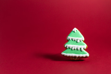 gingerbread cookie of green Christmas Tree on red background. Traditional Christmas food. Christmas and New Year holiday concept. Copyspace