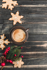 A Cup of coffee with foam on a dark wooden background with gingerbread in the form of snowflakes. New year and Christmas mood.
