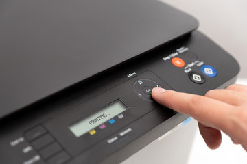 Hand pressing button on panel of printer